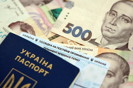 Ukrainian residence permit card or permanent resident card with passport on Ukrainian money close up