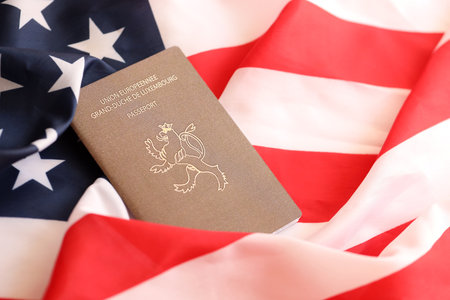 Luxembourg passport on big waving flag of United States of America close up.の写真素材