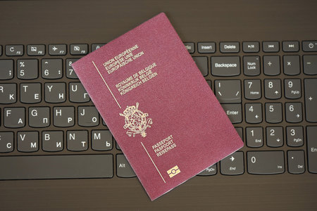 Belgium passport lies on black laptop keyboard buttons background close up. Technologies and control in Europe conceptの写真素材