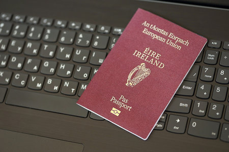 Ireland passport lies on black laptop keyboard buttons background close up. Technologies and control in Europe conceptの写真素材