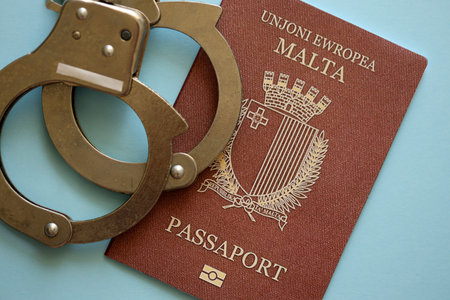 Malta passport with police handcuffs on table close up. Criminal level and arrests in Europe conceptの写真素材