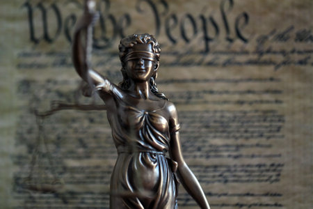 Dark scene with Lady Justice and background of US Constitution page close up. Lawsuit and judgement...