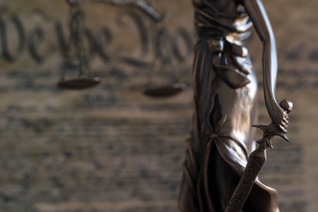 Dark scene with Lady Justice and US Constitution page close up. Lawsuit and judgement in United States of Americaの写真素材