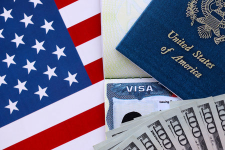 Passport and US Visa for immigration with many money bills close up on USA flag. Concept of immigration visa and taxes for travelの写真素材