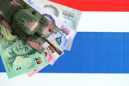 Thai baht currency money bills and toy tank on flag close up.の写真素材