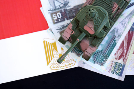 Egyptian pound currency money bills and toy tank on flag close up.の写真素材