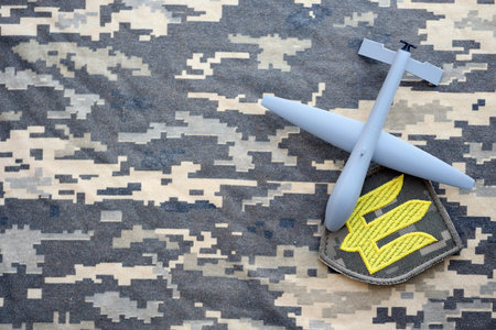 Unnamed grey toy drone model and Ukrainian Armed Force patch on camouflage fabric close upの写真素材