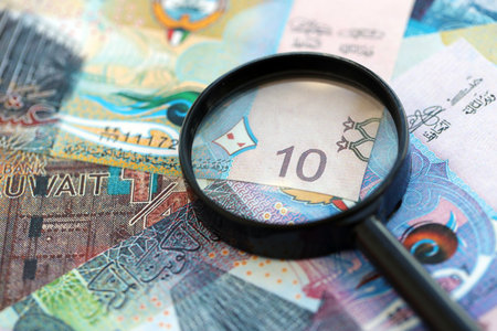 Kuwaiti dinar currency money bills and magnifying glass close up. The concept of financial...