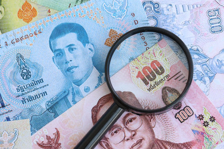 Thai baht currency money bills and magnifying glass close up. The concept of financial monitoring...