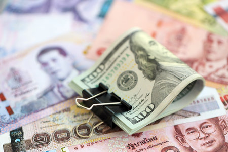 Thai baht currency money bills and bunch of us dollar banknotes close up. The concept of economics...