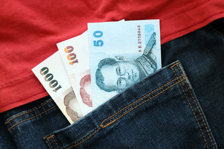 Thai baht money bills in denims pocket close up. The concept of fashion and wealthの写真素材