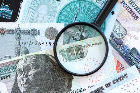Egyptian pound currency money bills and magnifying glass close up. The concept of financial monitoring and taxationの写真素材