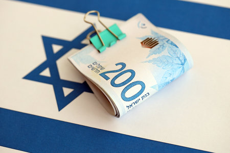 Israel New Shekels banknotes on national flag. The current Israel money bills lies on flag in big amount. The concept of business and investment in Israelの写真素材