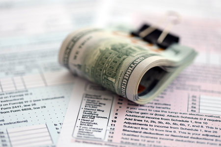 Big amount of United States hundred dollar bills on table with individual income tax return form...