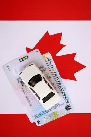 Canadian driving permit concept. Toy car and driver license on flag close upの写真素材