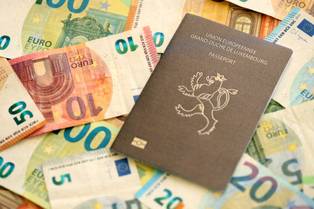 Luxembourg passport lies on big amount of euro money banknotes close up. Rich life and travel in Europe conceptの写真素材