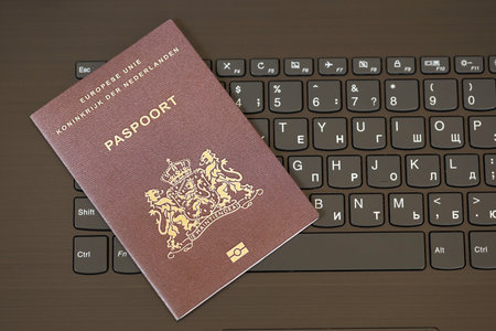 Netherlands passport lies on black laptop keyboard buttons background close up. Technologies and control in Europe conceptの写真素材