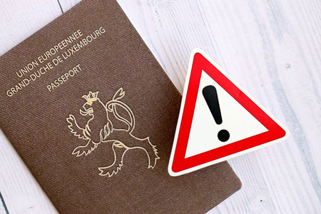 Luxembourg passport with exclamation sign on white wooden background close up. Problems with citizenship in Europe conceptの写真素材