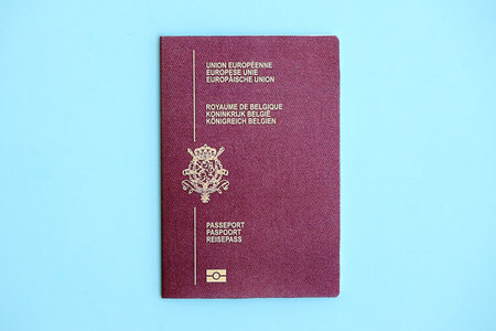 Belgium passport on light blue paper background close up. Citizenship and travel in Europe concept