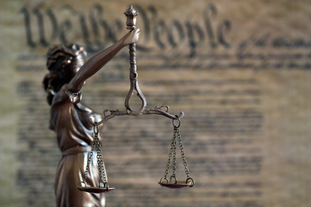 Low key scene with Lady Justice and backdrop of US Constitution page close up. Lawsuit and judgement...