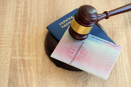 German temporary Permanent resident card and Ukrainian passport lies with judge hammer close up. Fiktionsbescheinigungの写真素材
