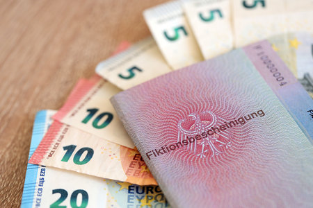German temporary Permanent resident card specimen and euro money bills lies on wooden table close up. Fiktionsbescheinigungの写真素材