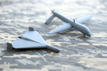 Unnamed grey toy drones models on camouflage fabric close up.