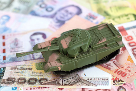 Thai baht currency money bills and toy tank close up. The concept of army funds and weapons salesの写真素材