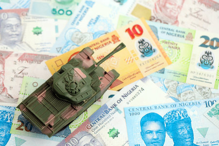 Nigerian naira currency money bills and toy tank close up. The concept of army funds and weapons...