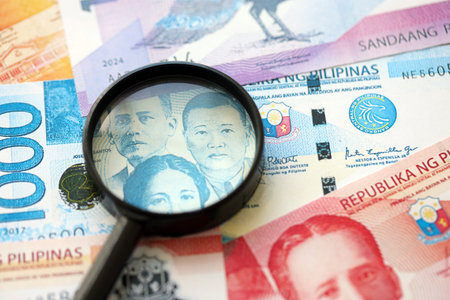 Philippines peso currency money bills and magnifying glass close up. The concept of financial...
