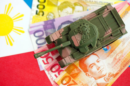 Philippines peso currency money bills and toy tank on flag close up.の写真素材