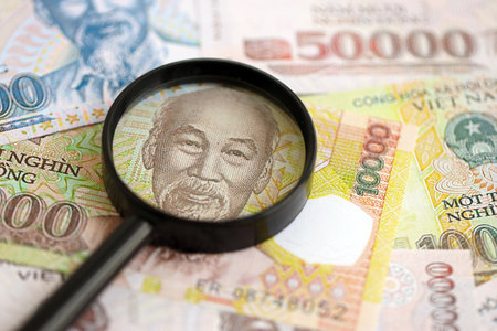 Vietnamese dong currency money bills and magnifying glass close up. The concept of financial monitoring and taxationの写真素材