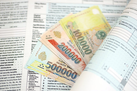 Vietnamese dong money bills on tax form close up. Taxation and accounting conceptの写真素材