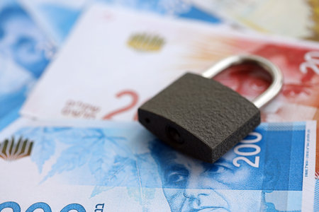 New Shekels banknotes and padlock. The current money bills and lock lies on table in big amount. The...