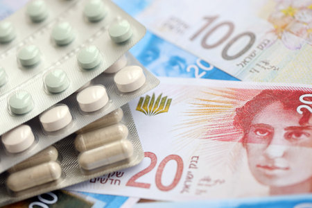 Israel New Shekels banknotes and medicine pills. The current Israel money bills and drugs lies on table in big amount. The concept of medicine and pharmacy in Israelの写真素材