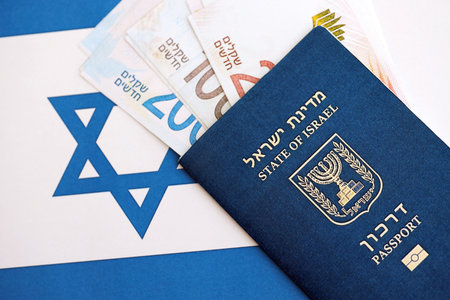 Israel New Shekels banknotes and passport on flag. The current Israel money bills and biometrical...