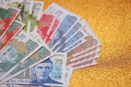 Pakistan rupees banknotes on golden yellow background. The current Pakistan money bills lies on table in big amount. The concept of business and investment in Pakistanの写真素材