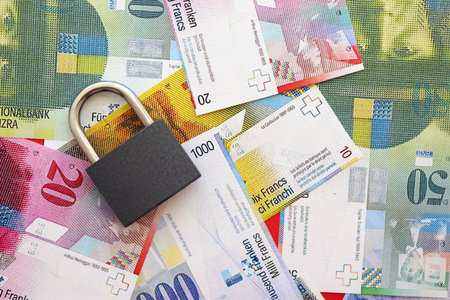 Swiss franc banknotes and padlock. The current francs money bills with lock lies on table in big...
