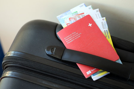 Swiss passport and franc money bills on travel bag. Pass and banknotes on bag close up. The concept of travel and vacation in Switzerlandの写真素材
