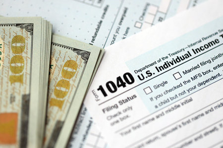 Hundred dollar bills and 1040 individual income tax return form blank close up. Few usd notes and...