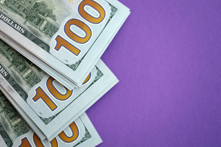Big amount of United States hundred dollar bills on purple background. Concept of taxation and money...