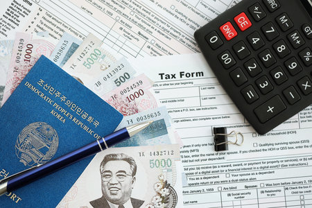 North Korean won money bills in big amount lies on table with pen, calculator, passport and tax forms close up. Taxpaying and accounting conceptの写真素材