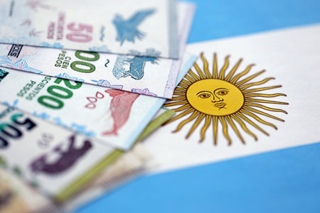 Argentine pesos money bills in big amount lies on Argentina flag close up. Finance and banking conceptの写真素材
