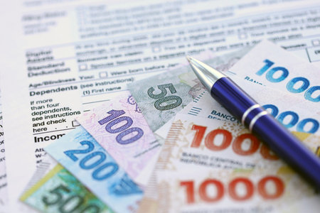 Argentine pesos money bills in big amount lies on table with pen and tax forms close up. Finance and banking conceptの写真素材