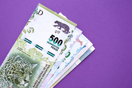 Argentine pesos money bills in big amount lies on purple color table close up. Finance and banking conceptの写真素材