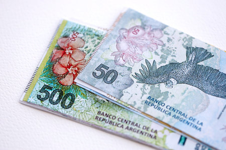 Argentine pesos money bills in big amount lies on white table close up. Finance and banking concept