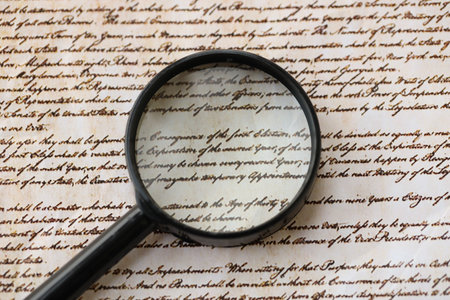 American USA Constitution paper page and magnifying glass close up. We The People