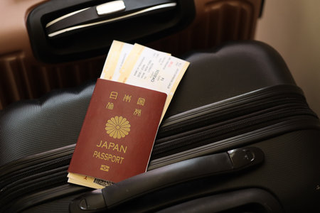 Japanese passport with tickets lies on touristic suitcase close up in airport waiting hall. Travel worldwide and international tourism conceptの写真素材