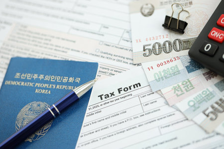 North Korean won money bills in big amount lies on table with pen, calculator, passport and tax...