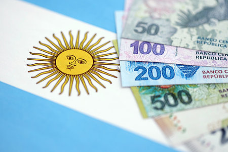 Argentine pesos money bills in big amount lies on Argentina flag close up. Finance and banking conceptの写真素材